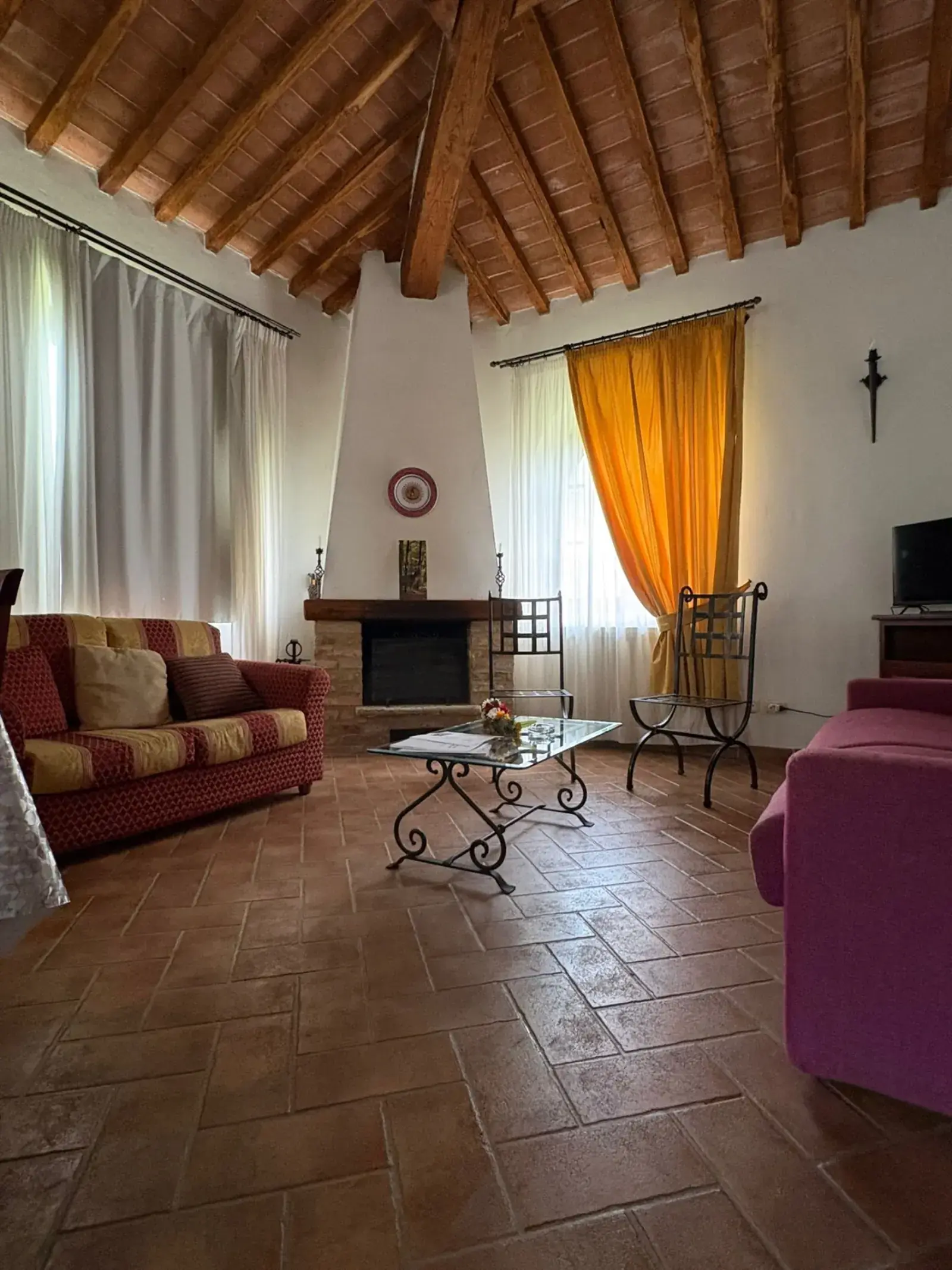 Soggiorno con camino in pietra, divani aspirati e tavolino in vetro lucidato.